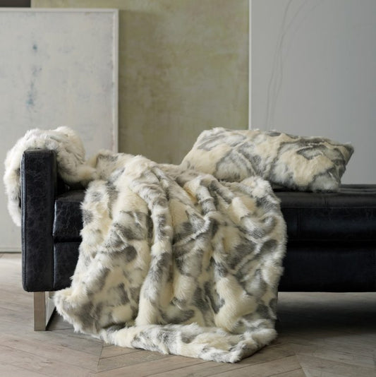 White and gray faux fur throw and pillow over black leather seating