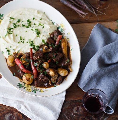 A plate full of mashed potatoes and beef stew