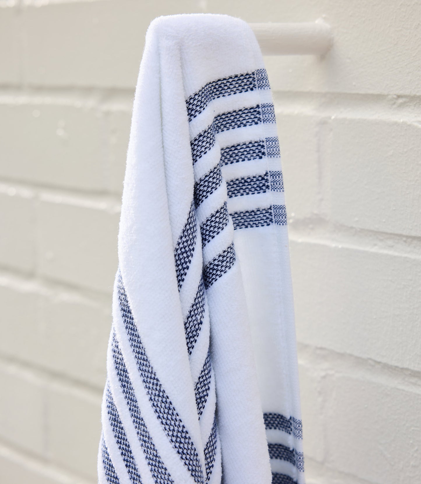 Aegean Beach Towel in Navy draped over a white hook, Navy