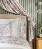 Close up of chloe percale shams on a bed against a draped, green accent wall