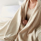 Woman wrapped in Favorite Reversible Cotton Blanket in Linen color