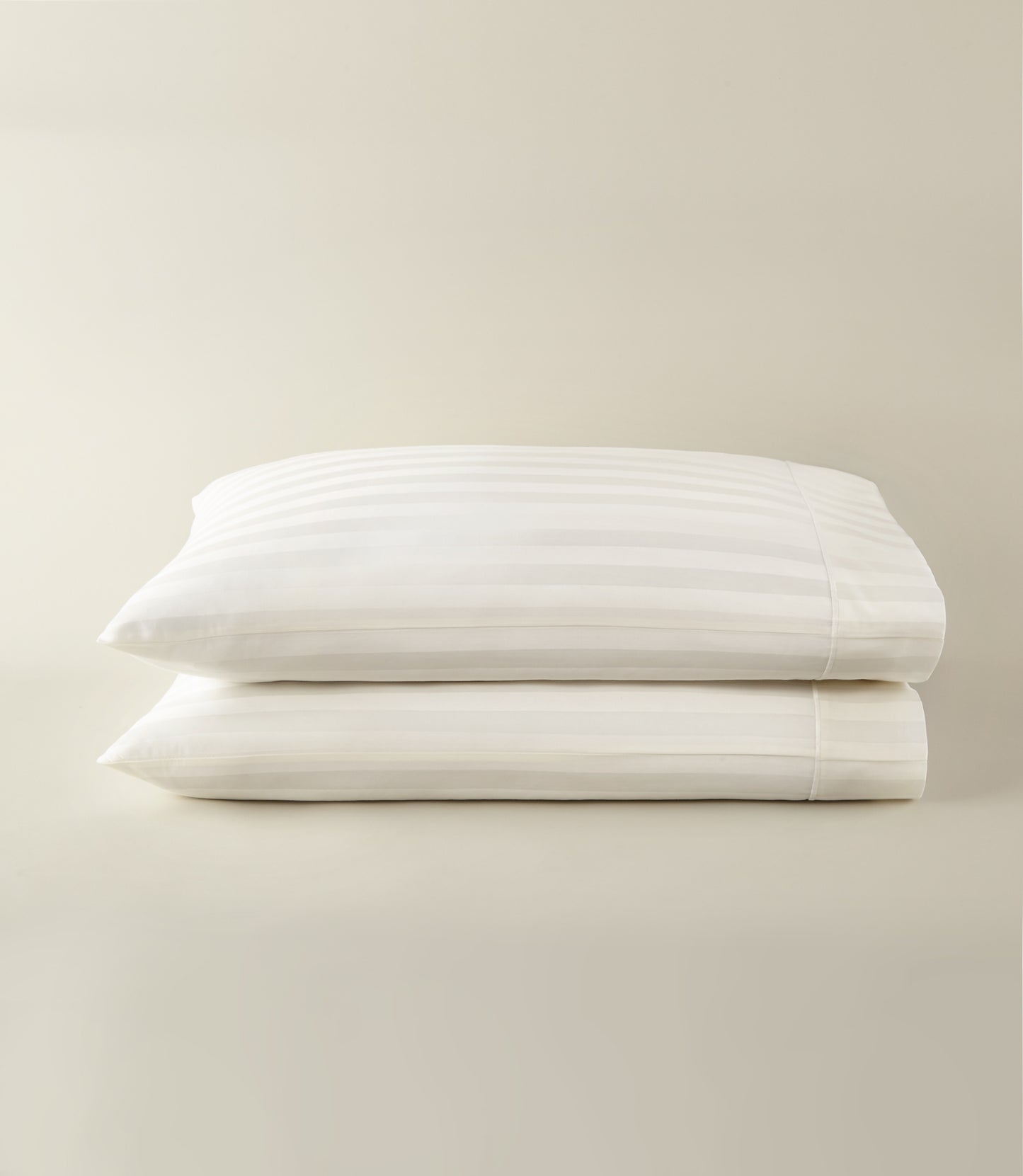 Soprano Stripe Sateen Pillowcases stacked on a beige background, Ivory