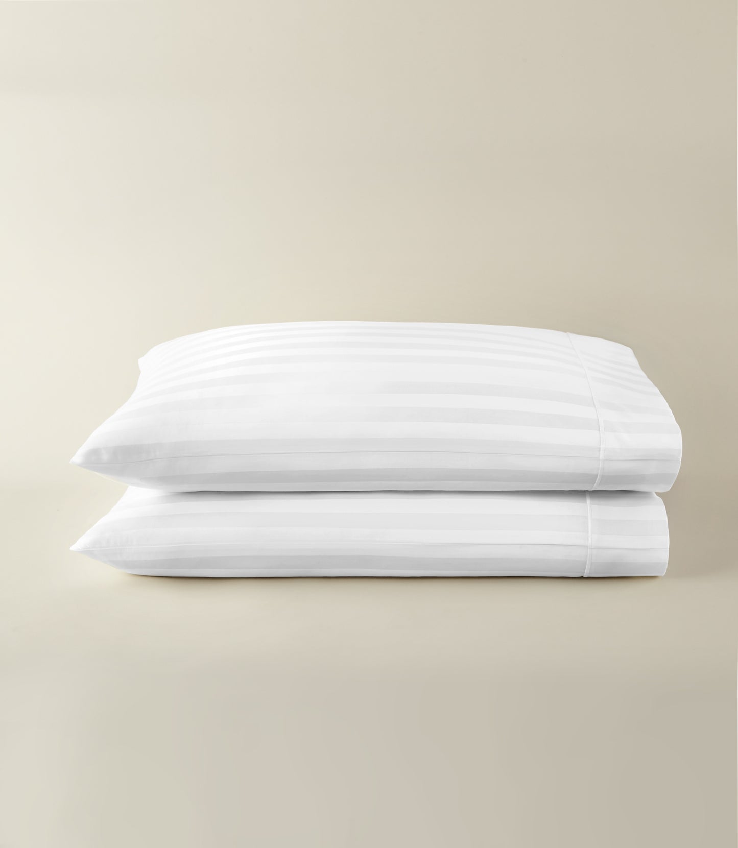 Soprano Stripe Sateen Pillowcases stacked on a beige background, White
