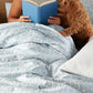 Woman in Bed Reading a Book with Dog and Fern Duvet Cover in Denim