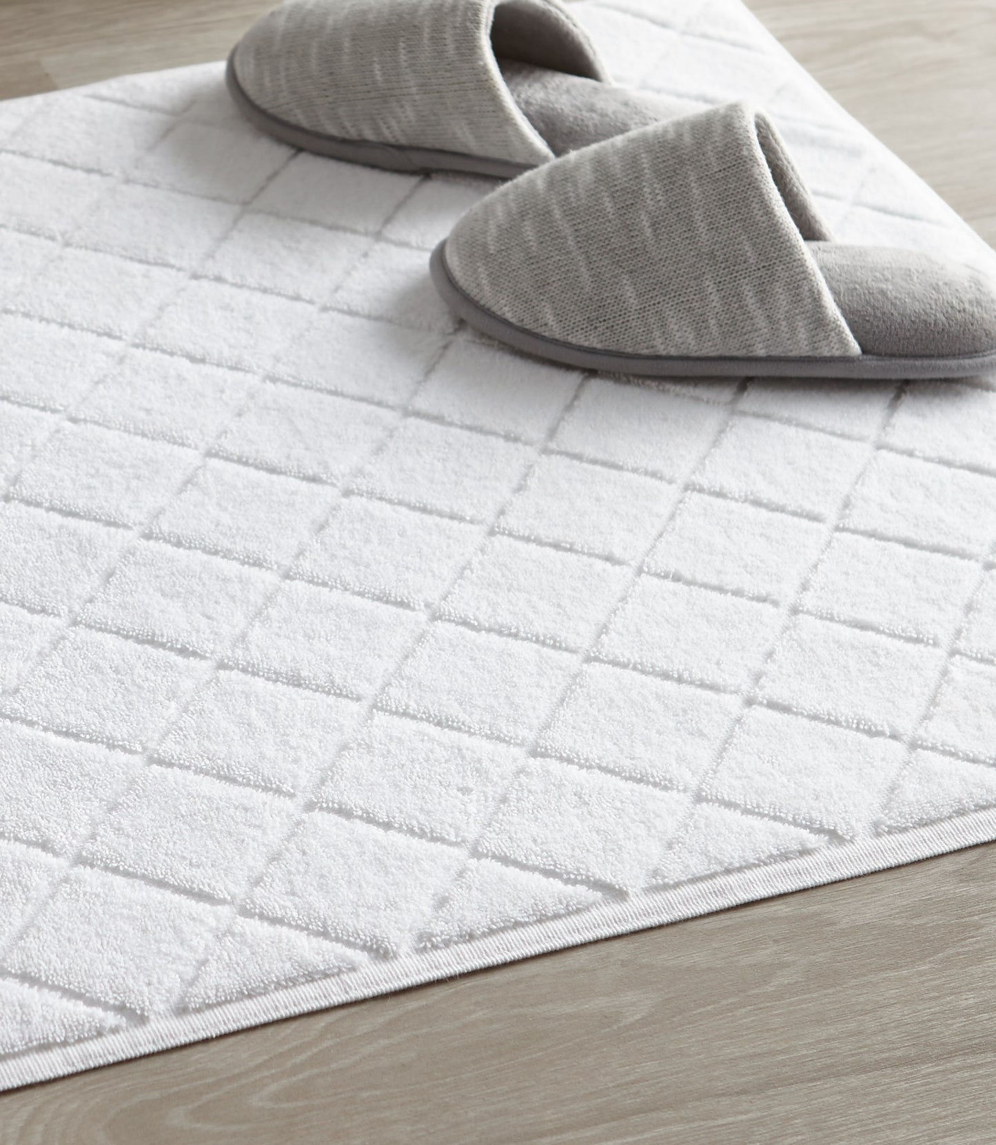 White slippers on top of lattice bath rug