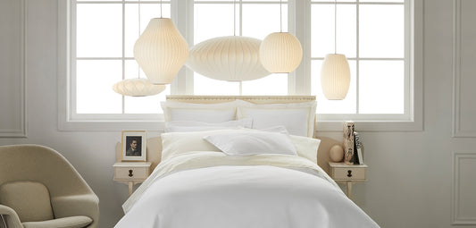 all white bed with sculptural lanterns over 