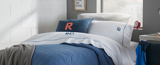 Peacock Alley monogrammed dorm bedding with blue quilt, white sheets and personalized pillows