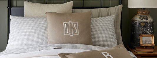 Display of tan and beige pillow shams on a bed.