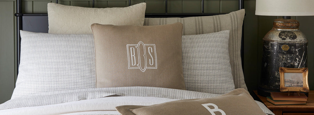 Display of tan and beige pillow shams on a bed.