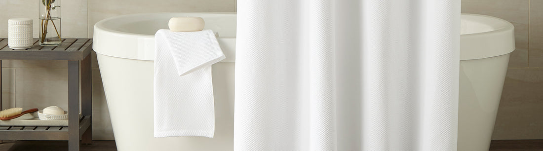 white shower curtain and towels on bath tub