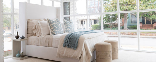 neutral bed with blue blanket in bright room
