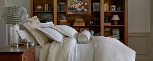 :Layered luxury bedding featuring neutral tones with pillows, duvet and blanket