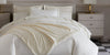 Soprano Stripe Sateen Duvet, styled with a cream colored throw in a light, modern room.