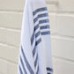 Aegean Beach Towel in Navy draped over a white hook, Navy