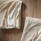 Folded Alta Reversible Cotton Blanket On Table White Pearl Colors