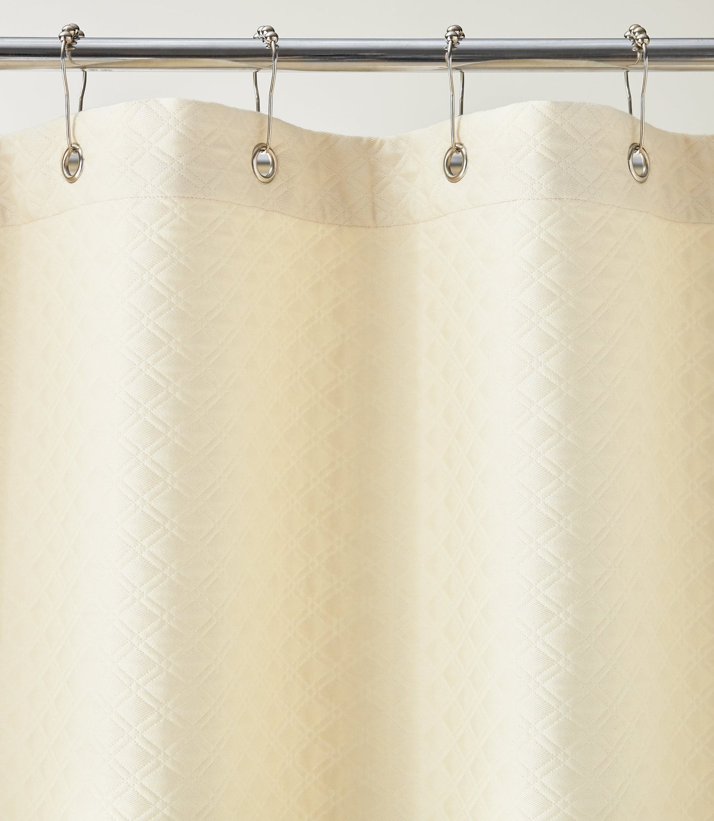 Detail of Alyssa Matelassé Shower Curtain with silver rings on a rod against a white background, Natural