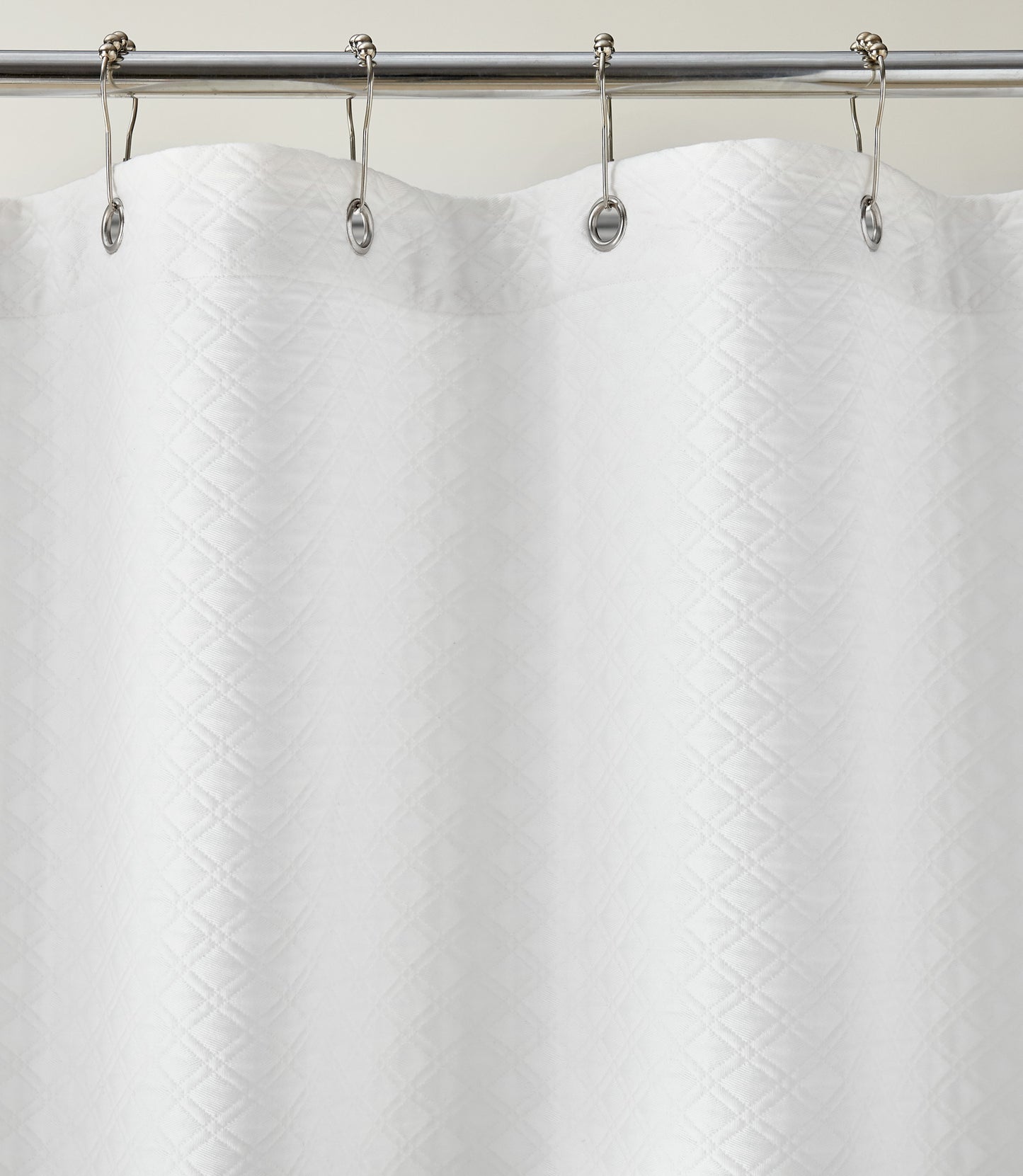 Detail of Alyssa Matelassé Shower Curtain with silver rings on a rod against a white background, White