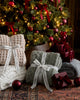Cozy waffle and knit blankets wrapped with ribbon, under a Christmas tree. 