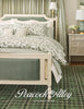Green bedroom with floral bedding and 'Peacock Alley' logo