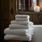 Catalina Bath Towel Set stacked atop a wooden stool, Linen