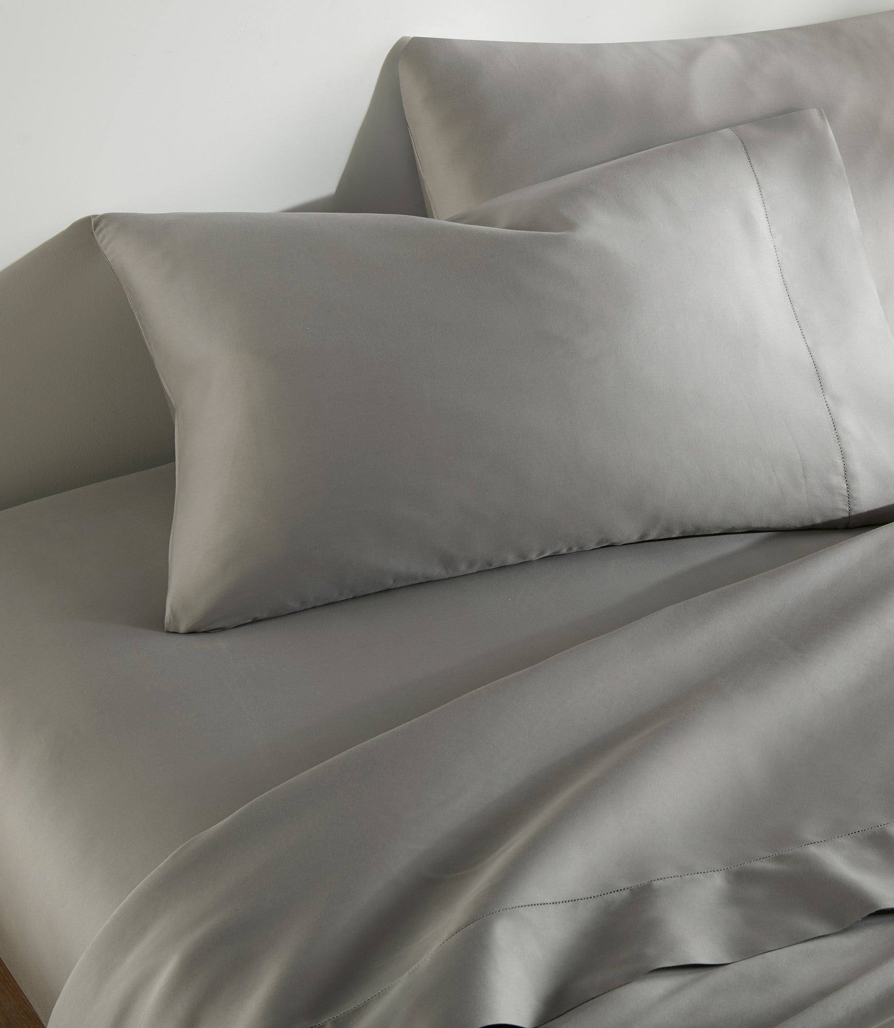 Clara Sateen Sheet Set and Pillowcases in Light Gray on bed 