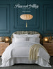 Peacock Alley 2026 Catalog cover with a bedroom scene featuring an all white bed and throw blanket.