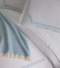 Close-up of satin stitch trim on the Deco Classic Embroidered Duvet Set in Sky and a light blue blanket.