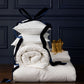 Stack of Down Alternative Duvet and Pillows with navy ribbons against a dark paneled wall