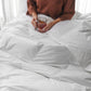 Woman sitting in bed with down alternative duvet, White