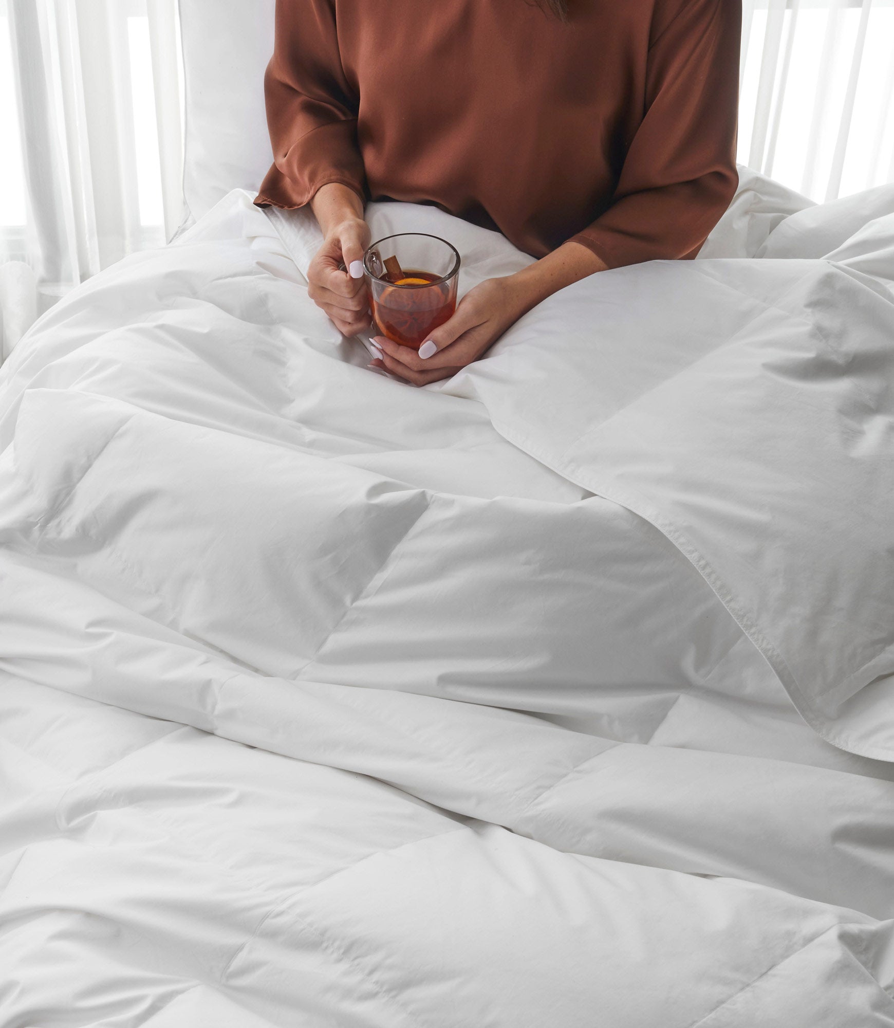 Woman sitting in bed with down alternative duvet, White