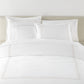 Filigree Duvet Set arranged on a bed against a light beige headboard, Linen