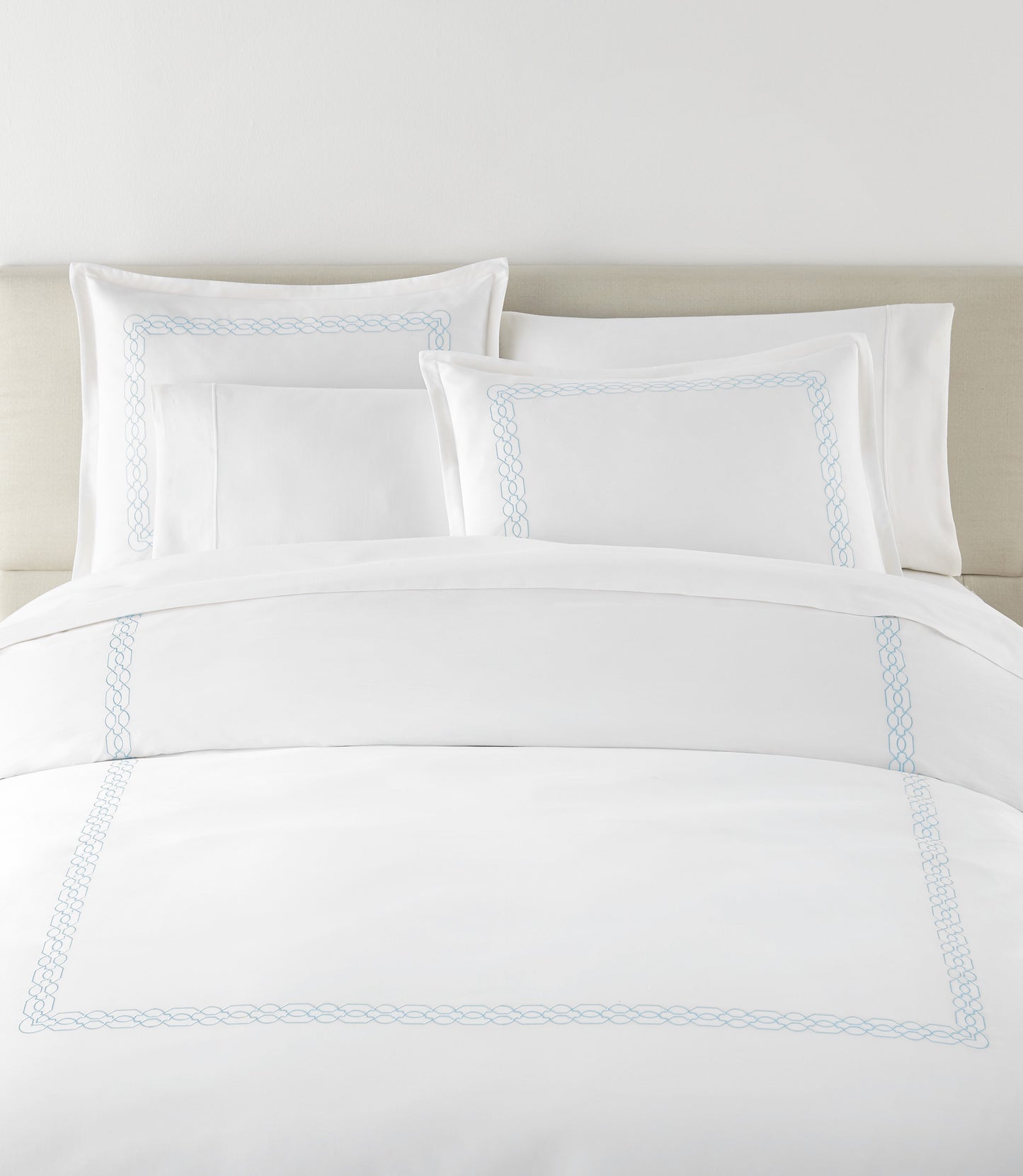 Filigree Duvet Set arranged on a bed against a light beige headboard, Sky