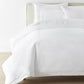 Filigree Duvet Set arranged on a bed against a white wall, White