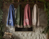 Four Verona Wool Throw blankets in blue, green, rose, and linen hanging from stone mantel.