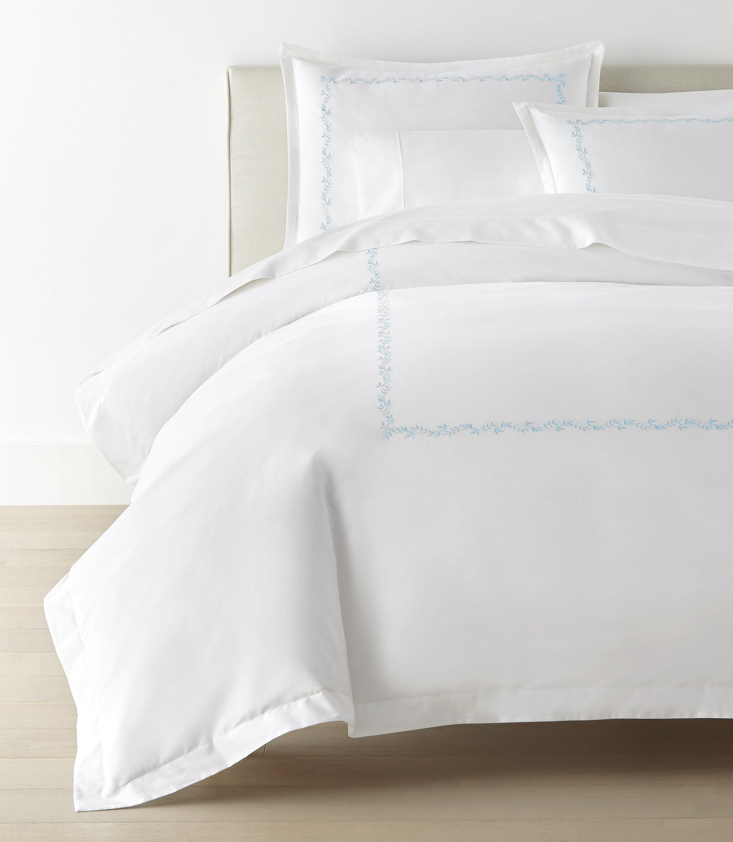 Ivy Classic Embroidered Duvet Set displayed on a bed with a cream colored headboard, Sky