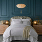Neatly made bed with Ivy Classic Embroidered Duvet Set and a beige throw blanket in a bedroom with blue paneled walls.