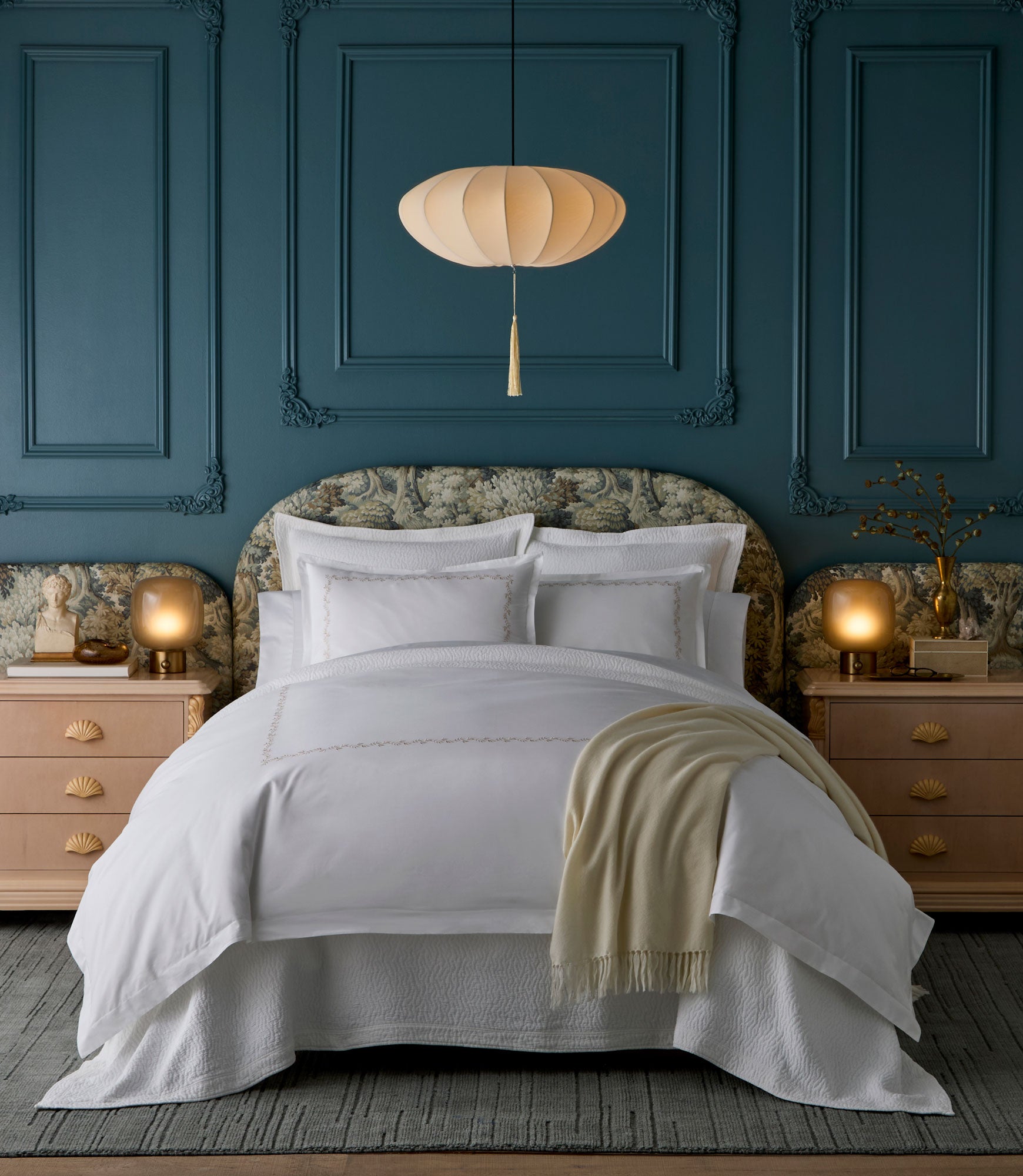 Neatly made bed with Ivy Classic Embroidered Duvet Set and a beige throw blanket in a bedroom with blue paneled walls.