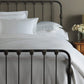 Oxford Matelassé Coverlet displayed on an iron frame bed, White