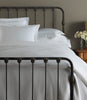 Oxford Matelassé Coverlet displayed on an iron frame bed, White