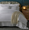 Ivy Classic Embroidered Duvet Set in a styled bedroom with a patterned headboard, blue wall, and wooden nightstand with a glowing lamp.
