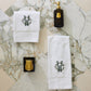 Special Occasion Towel Gift Set in White with monogram design, black soap dispenser, and gold candle on a marble surface 
