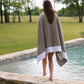 Soleil beach towel with white trim wrapped around model stepping into a pool