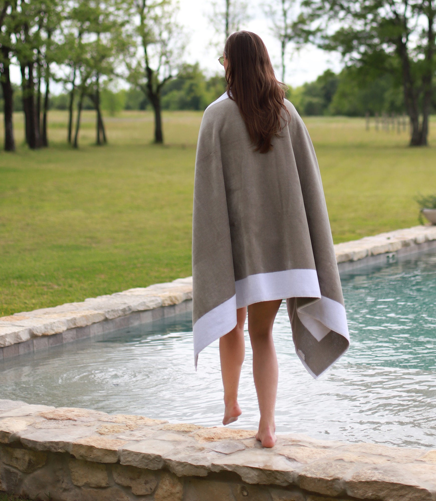 Soleil beach towel with white trim wrapped around model stepping into a pool