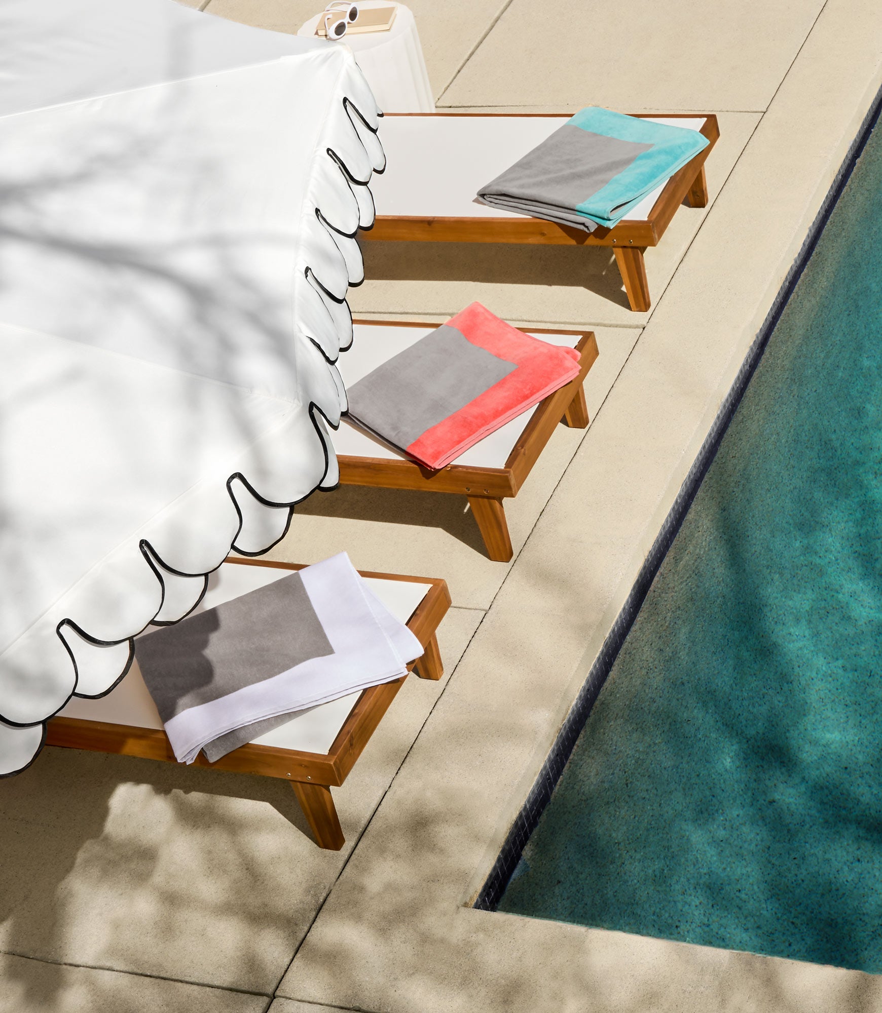 Soleil beach towels laid out on three lounge chairs by the pool