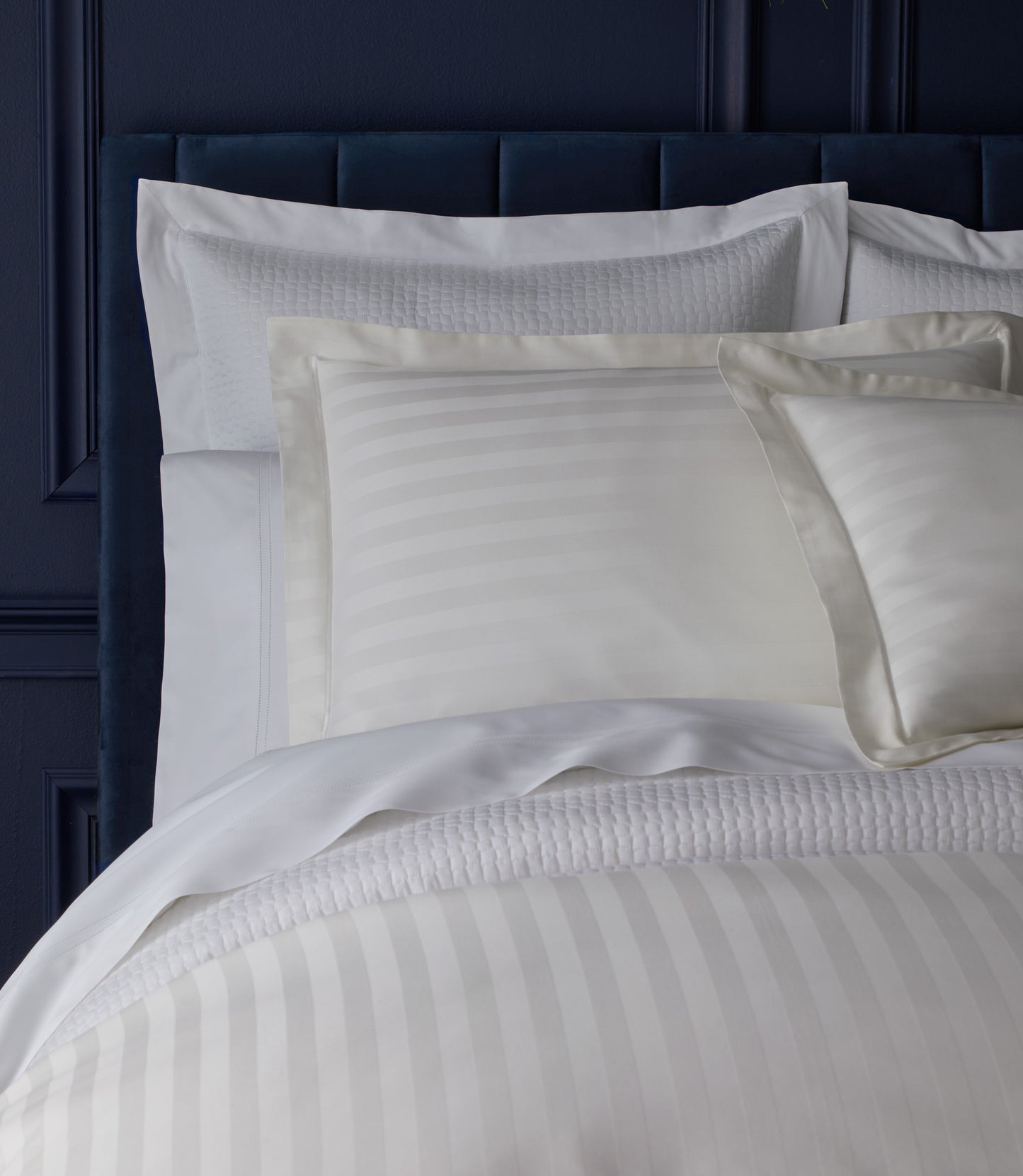 Soprano Striped Sham on a bed with a dark blue headboard