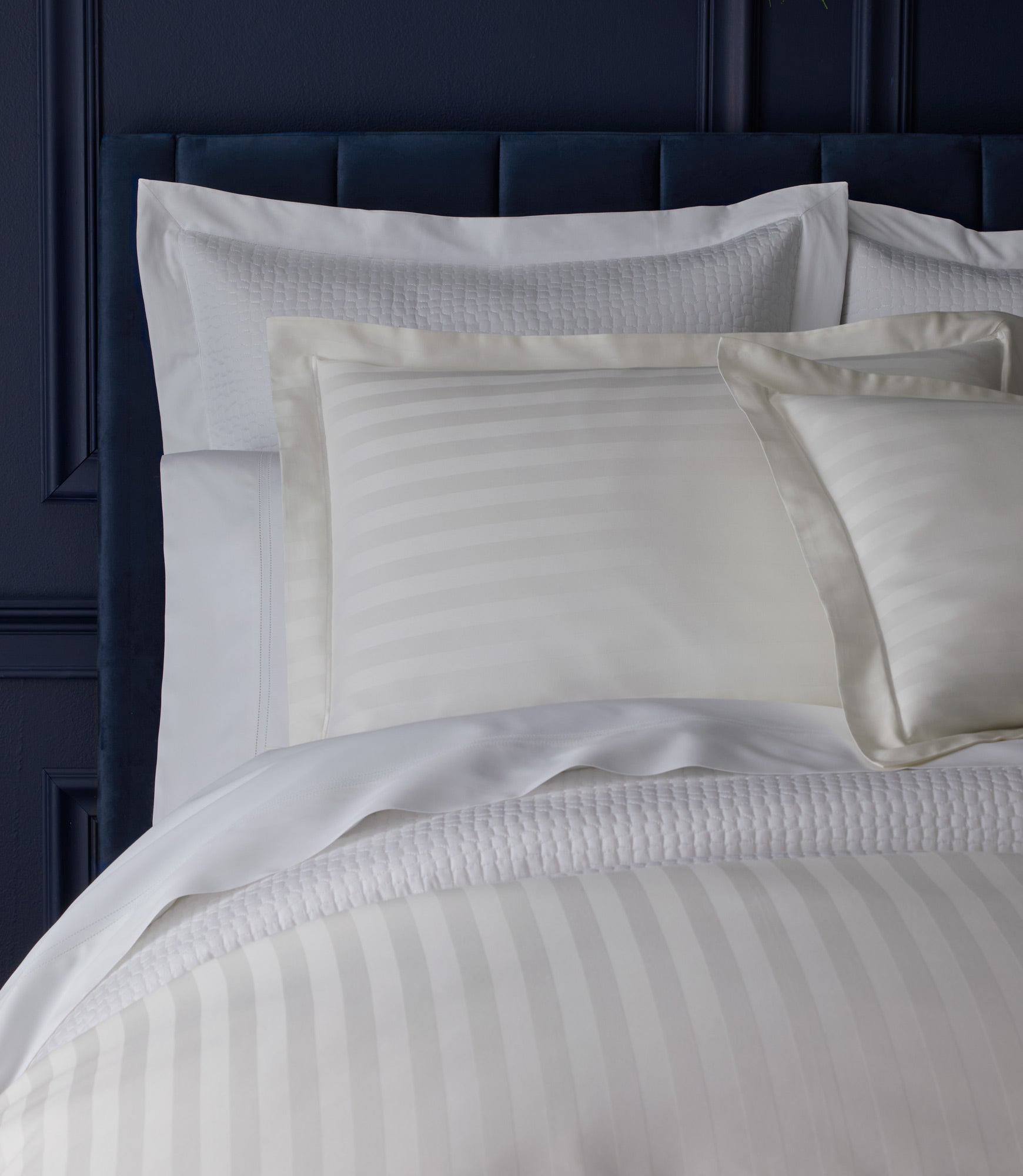 Soprano Striped Sham on a bed with a dark blue headboard