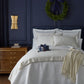 Neatly made bed with Soprano Striped Duvet Set and a decorative wreath on a navy blue wall.