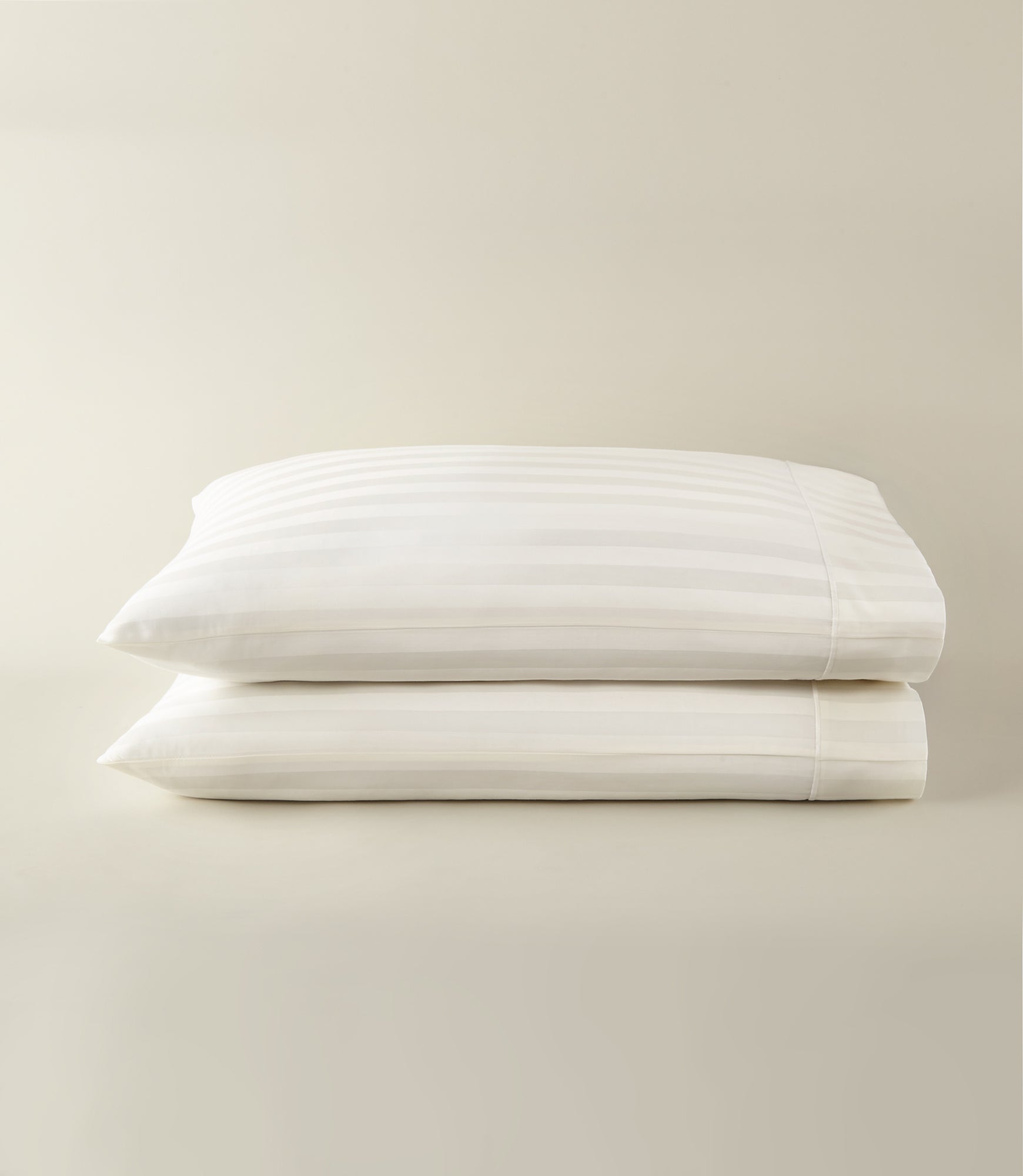 Soprano Stripe Sateen Pillowcases stacked on a beige background, Ivory
