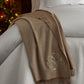 Verona Throw Blanket in Oat monogrammed,  thrown over a white bed
