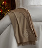 Verona Throw Blanket in Oat monogrammed,  thrown over a white bed